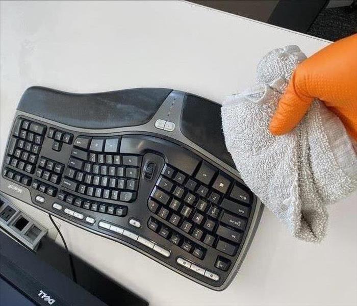 A SERVPRO technician is disinfecting a keyboard